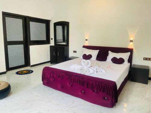 a bedroom with a large bed with a purple blanket at Amor Luse in Arugam Bay