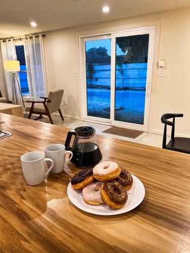a plate of donuts on a table with two cups at The Oasis - 2 Private Homes, Pool, and BBQ in New Port Richey