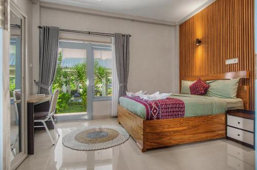 a bedroom with a bed and a desk and a window at Hotel Bonne Nuit in Labuan Bajo