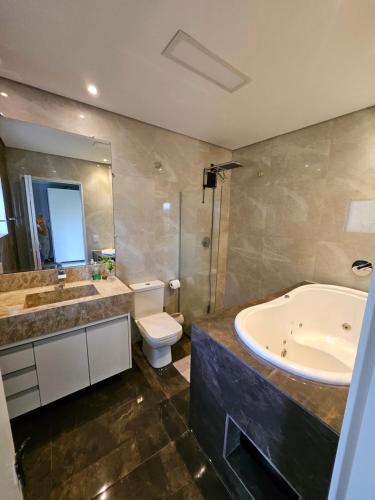 a bathroom with a tub and a toilet and a sink at Chácara Minas Garten in Jundiaí