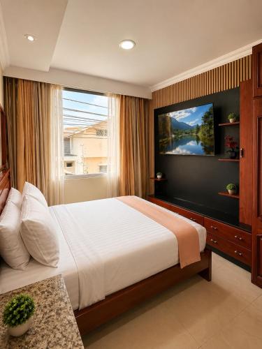 a bedroom with a large bed with a television on the wall at Suite Matrimonial con Piscina Desayuno Ambiente Exclusivo in Machala