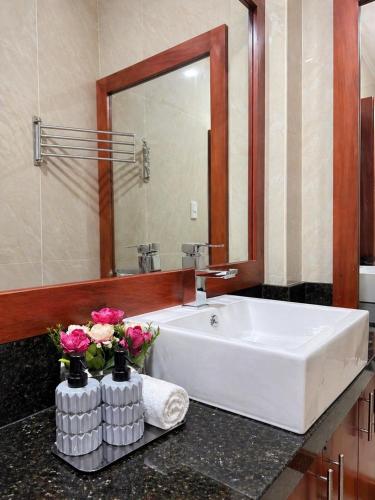 a bathroom with a white sink and flowers on a counter at Suite Matrimonial con Piscina Desayuno Ambiente Exclusivo in Machala