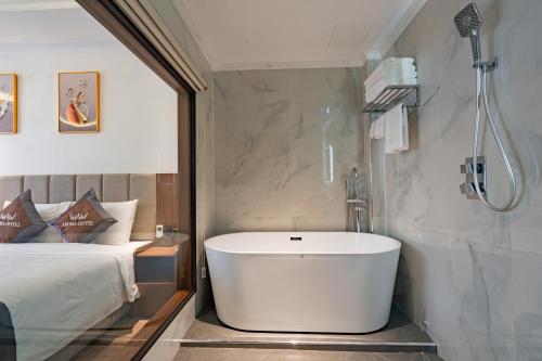 a bathroom with a bath tub next to a bed at Aroma Hotel An Khánh in Vân Lũng
