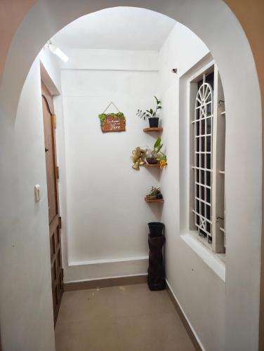 an arched hallway with a window and plants on the wall at Sky Loft in Trivandrum