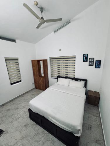 a bedroom with a white bed and a ceiling fan at Chills homestay in Kalpetta