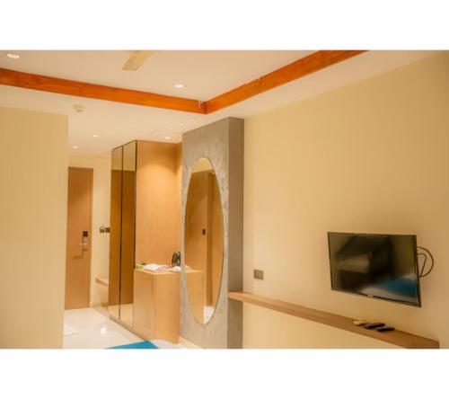 a bathroom with a mirror and a tv on a wall at Hotel Prince Residency, Bhuj in Bhuj