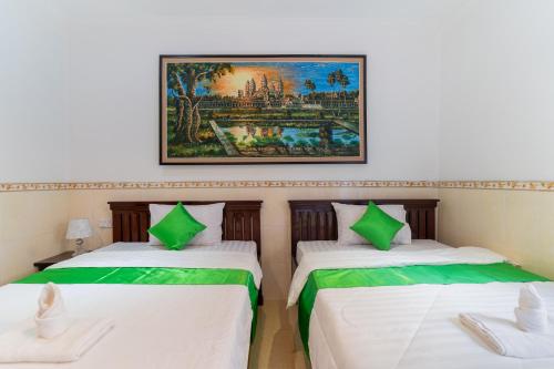 two beds in a room with a painting on the wall at 855 Villa Siem Reap in Siem Reap