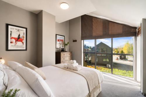 a bedroom with a white bed and a large window at Cardrona Sanctuary by Aotearoa Escapes in Cardrona