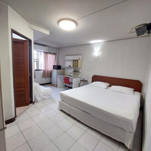 a bedroom with a large white bed and a desk at BaanSathorn21 in Bangkok