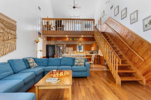 a living room with a blue couch and a staircase at 1602 - Here To Stay in Corolla