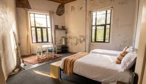 a bedroom with a bed and two windows at Nomaddicts in Mexico City