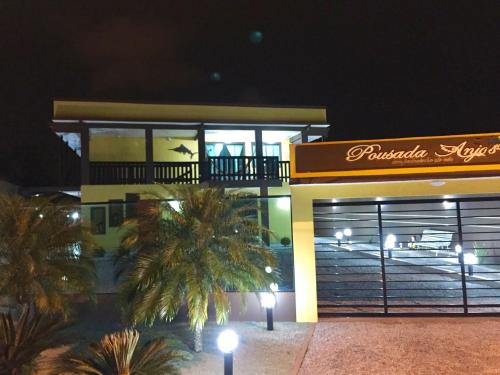 馬蒂尼奧斯的住宿－Pousada Anjos - à 2 quadras do mar，一座棕榈树在晚上的建筑