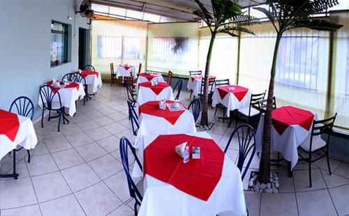 a restaurant with red and white tables and chairs at Vinte Park Hotel in Bragança Paulista
