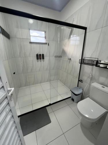 a white bathroom with a shower and a toilet at Pousada Viva Santo Amaro in Santo Amaro