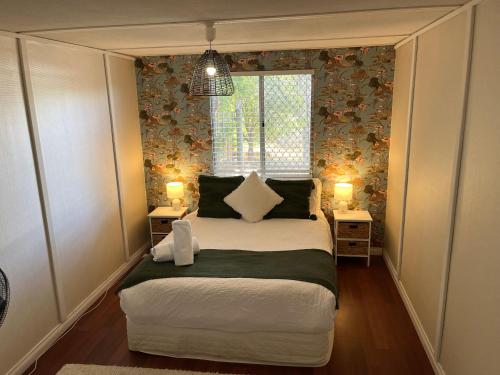 a small bedroom with a large bed with two lamps at The Cooby in Spearwood