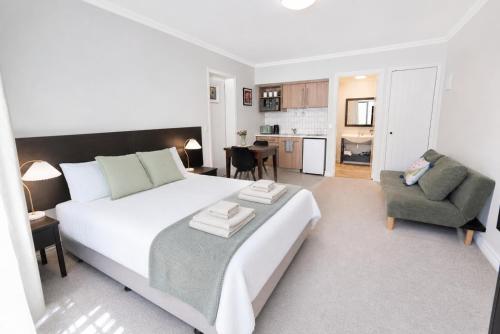 a bedroom with a large white bed and a chair at Alpine Cardrona by Aotearoa Escapes in Cardrona