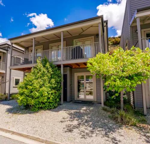 a house with a balcony and trees in front of it at Alpine Cardrona by Aotearoa Escapes in Cardrona