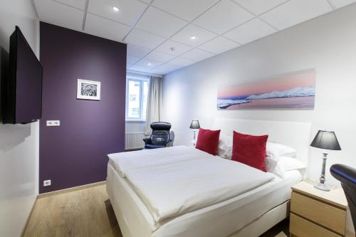 a bedroom with a large white bed with red pillows at Centrum Hotel in Akureyri