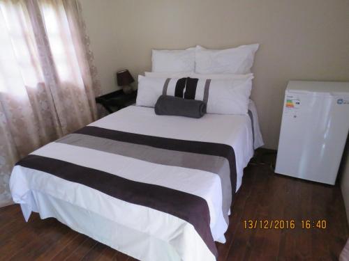 a bedroom with a large white bed with a bag on it at Klein Paradys Lodge - Polokwane in Polokwane