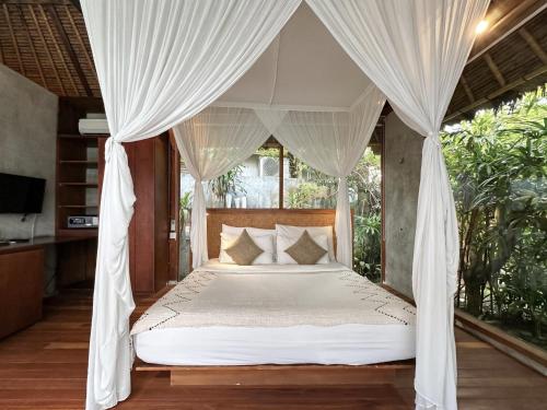a bedroom with a canopy bed with white drapes at ZIN Berawa Villas & Bungalows in Canggu