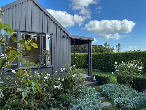 a garden with a grey house and some bushes at Tswalu in Raglan