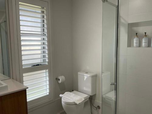 a white bathroom with a toilet and a shower at Chay's Guest House in Coffs Harbour