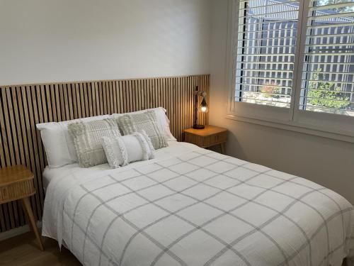 a bedroom with a white bed with pillows and a window at Chay's Guest House in Coffs Harbour