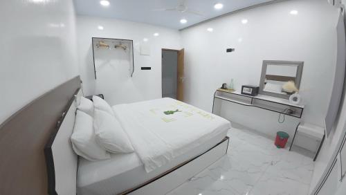 a white bedroom with a bed and a mirror at Skyinn omadhoo in Omadhoo