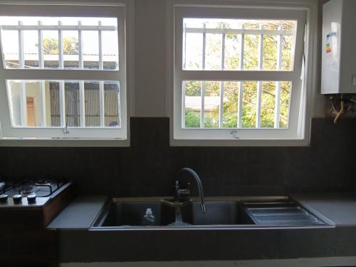 a kitchen with two windows above a sink at App F4 Kone centre RDC Tel 7O 55 O8 in Koné