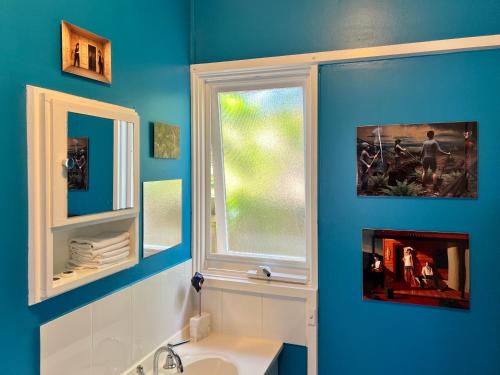 a blue bathroom with a sink and a window at & Art Motel in Tootgarook