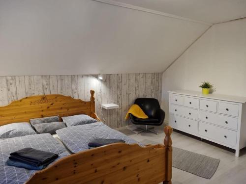 a bedroom with a wooden bed and a black chair at Villa Mio in Vidsel