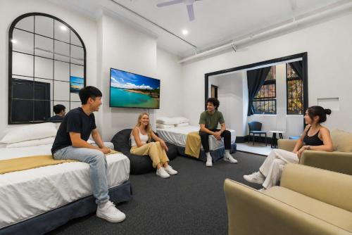a group of people sitting on beds in a room at London Gate Backpackers Hostel in Sydney