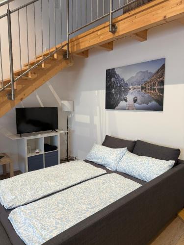 a living room with a bed and a staircase at SchwalbenNest Pfeifers OdenwaldNest in Rimbach