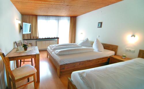 a bedroom with two beds and a table and a chair at Gasthof Bad Sonnenberg in Nüziders