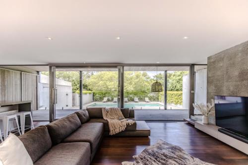 a living room with a large couch and a television at Thule Country Estate - Private Architect-Designed Farm Estate, 6 Bedrooms, Sleeps 12 in Mount Macedon