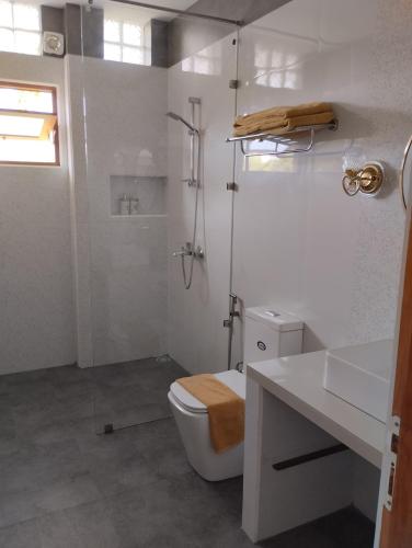 a white bathroom with a toilet and a shower at Weligama Ocean Breeze in Weligama