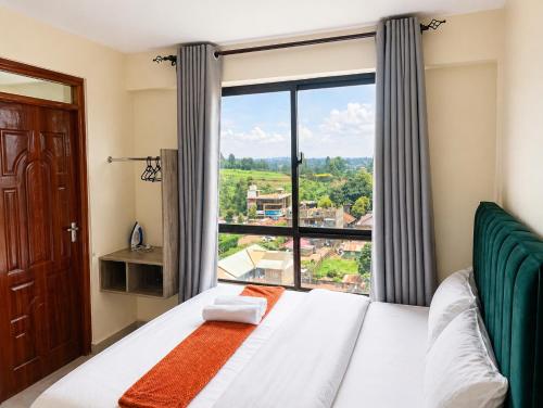 a bedroom with a bed and a large window at Modern Nest Studio Kikuyu in Rungiri