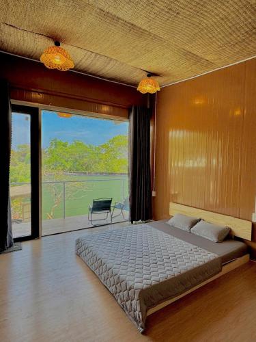 a bedroom with a large bed and a balcony at La An Homestay in Vĩnh Hy