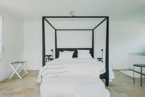 a bedroom with a large white bed with a black frame at Les Joyaux d'Eliane in Le Bernard