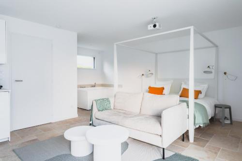 a bedroom with a white bed and a white couch and tables at Les Joyaux d'Eliane in Le Bernard