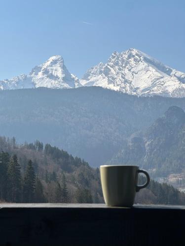 a coffee cup sitting on a window sill with a mountain at Ferienwohnung Bergidyll in Schönau am Königssee