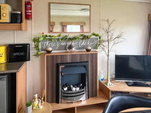 a living room with a fireplace and a mirror at Joys in Jaywick Sands