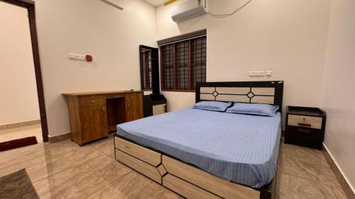 a bedroom with a bed with a blue comforter at Souparnika apartments in Varkala