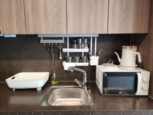 a kitchen counter with a sink and a microwave at Bona Together In Haeundae Residence in Busan
