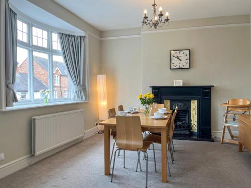 a dining room with a table and a fireplace at Victoria Apartment 1 in Tarporley