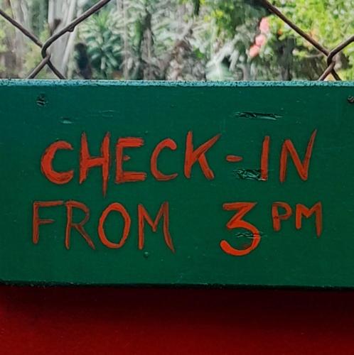 a green sign that reads check in from at At Home in Puerto Princesa City