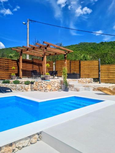 a swimming pool in a backyard with a wooden pergola at Kamena kuća Goranci in Mostar