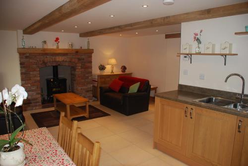 a kitchen and living room with a fireplace at Swallows Barn Cottage in North Rode