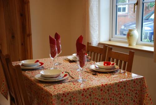 a table with plates and bowls and wine glasses on it at Swallows Barn Cottage in North Rode