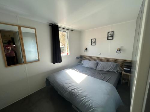 a small bedroom with a bed and a mirror at Le SaraLéna in Torreilles